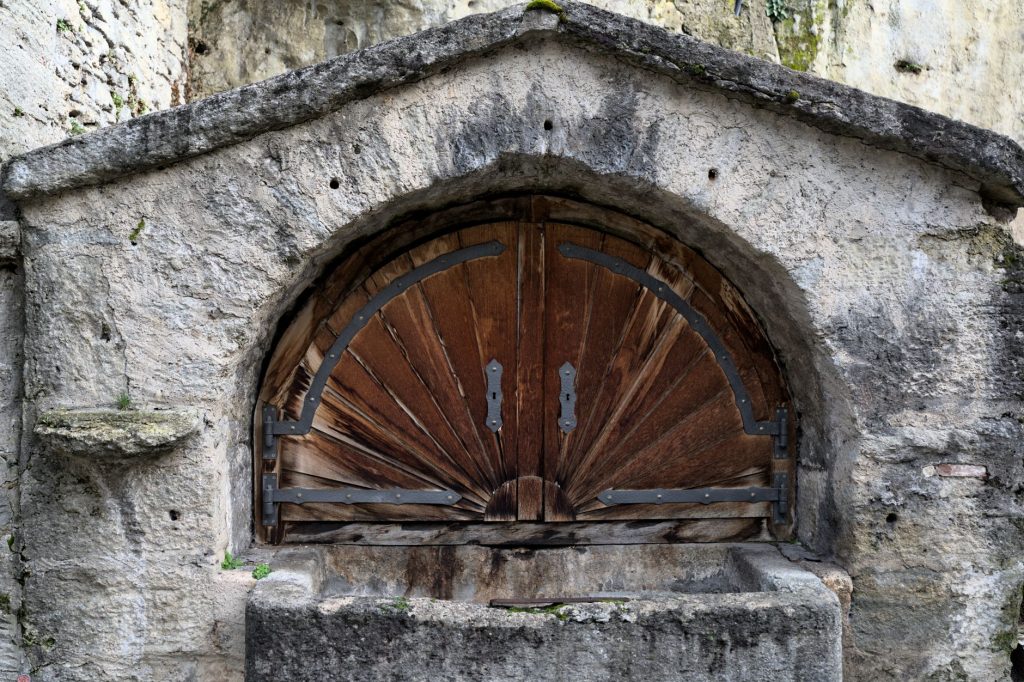 Porte en bois ancienne à panneaux moulurés dans une façade en pierre