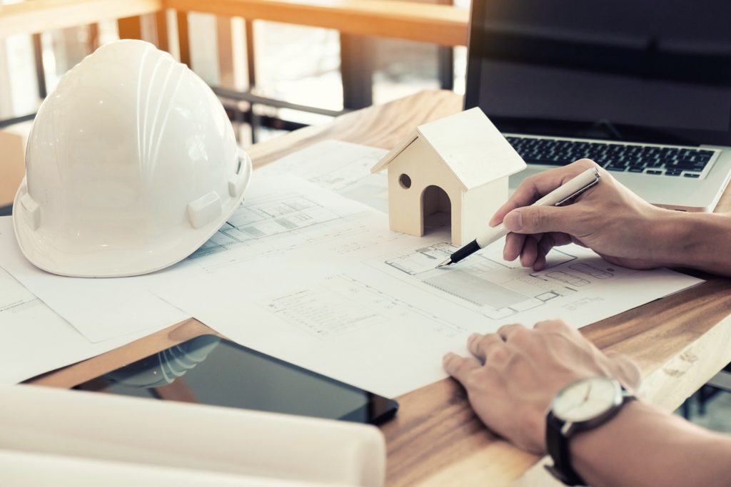 lingenieur-discute-a-la-table-avec-un-plan-de-construction-de-maison