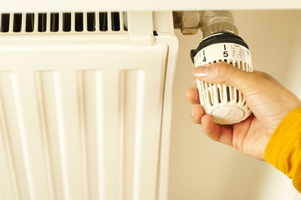 Main réglant le thermostat d'un radiateur