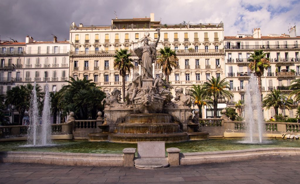 Rue commerçante et place animée dans le centre de Toulon, entre façades anciennes et vie de quartier