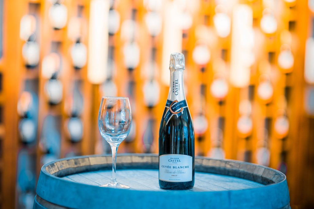 Bouteille de champagne posée sur un tonneau devant des casiers de cave