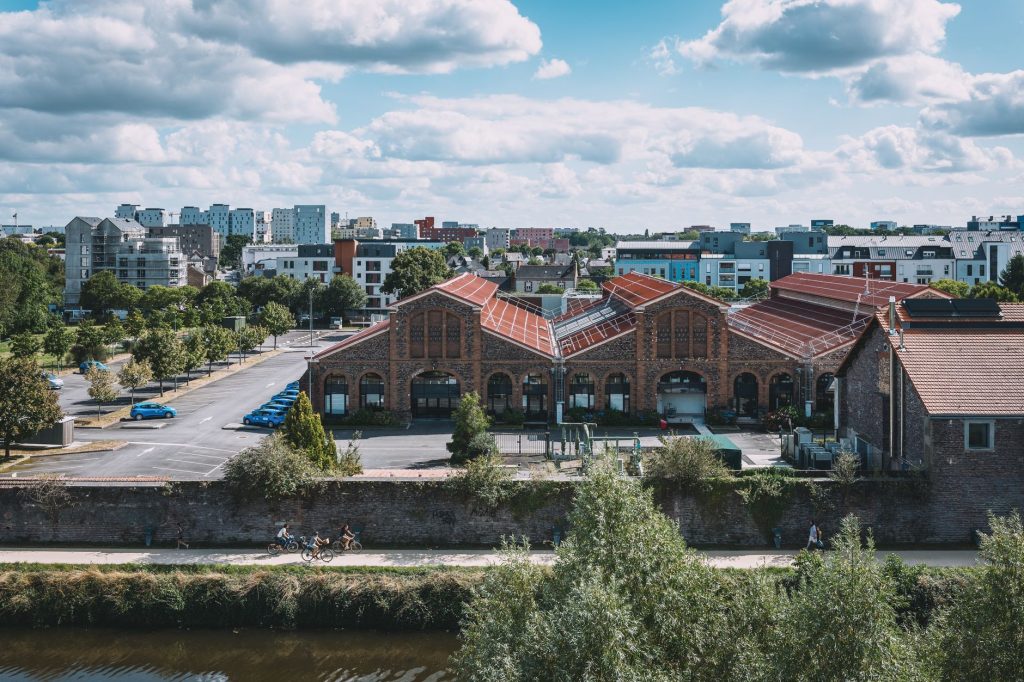 Anciennes halles industrielles en brique reconverties au bord d'un canal, typiques des villes textiles du Nord