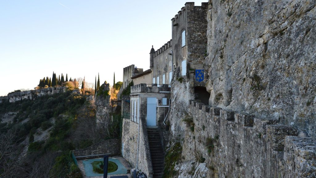 Château de pierre niché dans une falaise avec vue sur une vallée au crépuscule