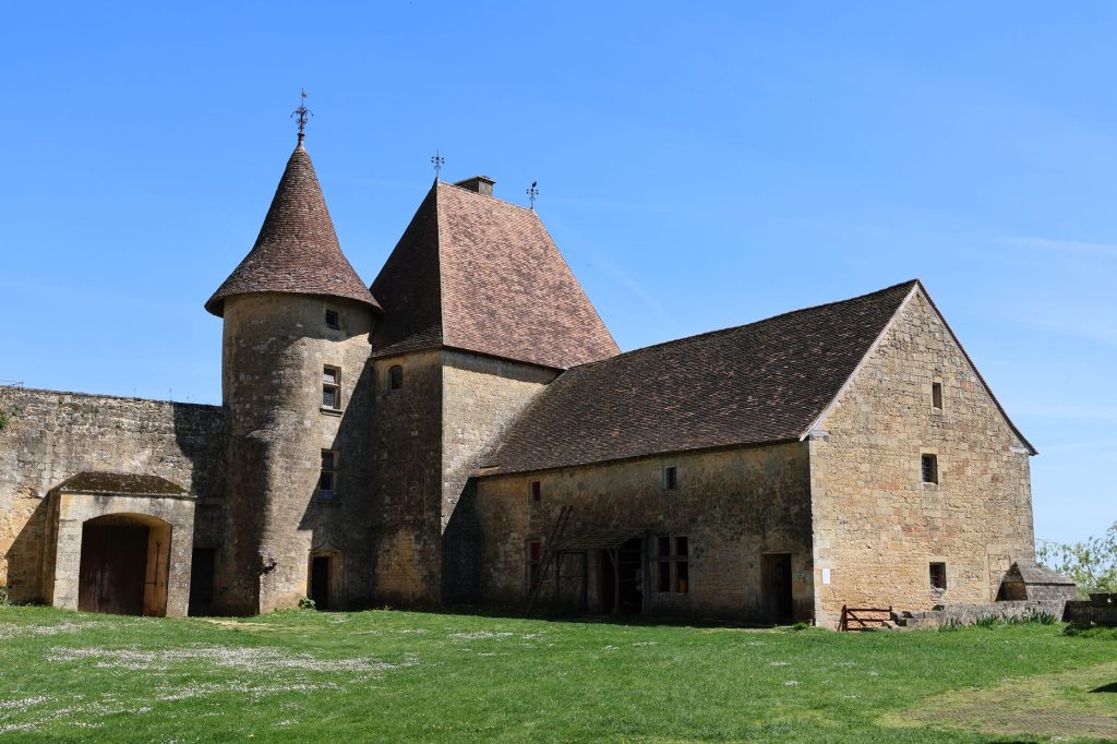 Château médiéval en pierre avec une tourelle et un toit en pente sous un ciel bleu